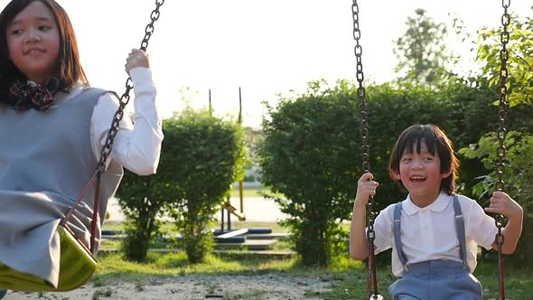 Asian Girl And Her Brother Playing Swing Together In The Park Slow Motion