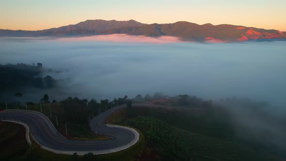 4K High mountain road in fog. Tropical forest with smoke and fog. Aerial view from drone