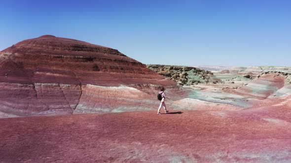 Cinematic Aerial Shot of Woman Walking By Red Sandstone Hills Traveler Backpack