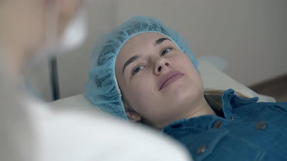 Client in Cap Talks with Cosmetologist About Eyebrows Style