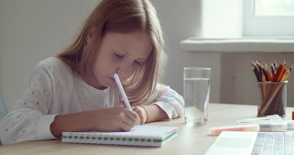 Close Up Little Schoolgirl Does Her Homework, Writes on Paper, Studies Remotely From Home in