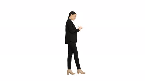 Concentrated Woman in a Suit Writing Business Ideas in Her Notepad While Walking on White Background