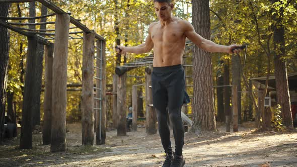 Best cardio workout. Muscular man training with skipping rope in the forest gym, outdoors