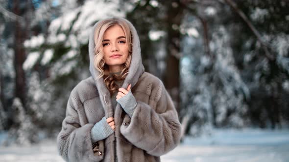 Cute Woman Wearing Hood Fur Coat Smiling Walking at Winter Forest