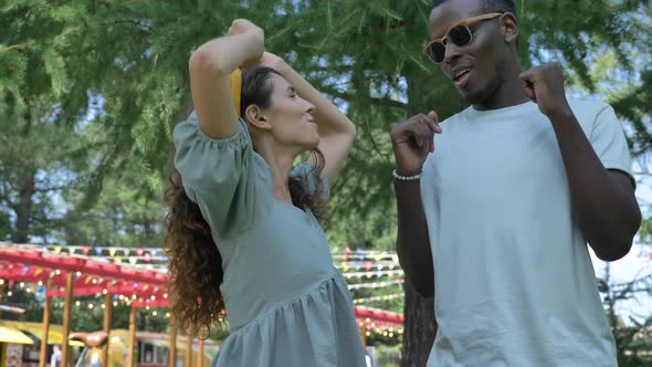 Brunette Woman and African American Man Dance at Park Tree