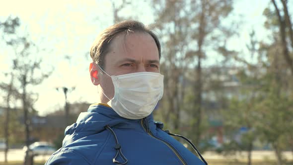 Portrait of Male Tourist Wearing a Protective Mask on a Street in a Park. Protection Against Viruses