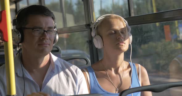 Woman and man listening music in headset during bus trip