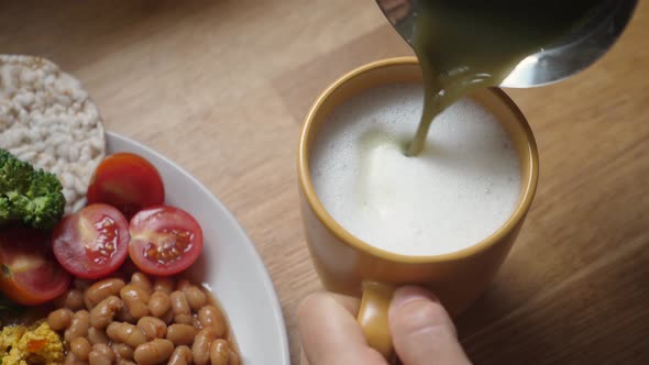 Top View of Pouring Matcha Tea Into Foamed Plant Based Milk. Healthy Vegan Breakfast