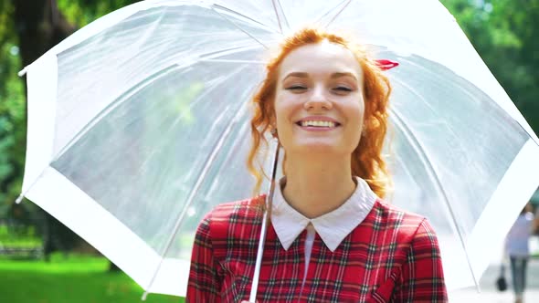 Red Haired Female Walking with Umbrella in the Sun