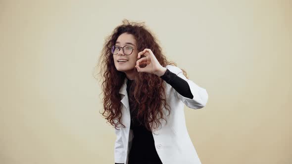 The Enthusiastic Young Woman with Curly Hair Shows Her Gesture Well with Her Hand and Winks