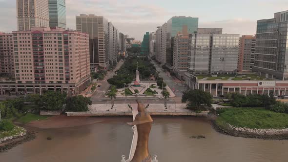 Rising aerial shot behind Kun Iam golden statue in NAPE business area in Macau