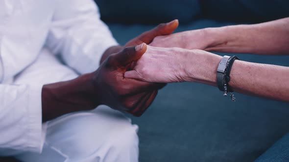 Close Up African American Black Doctor Holding Hand of Elderly Caucasian Woman