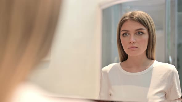 Rear View of Serious Young Woman Looking in the Mirror 