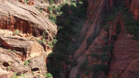 Group Of Hikers Climbing On Red Sandstone Cliff In St. George, Utah. drone forward shot