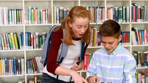 Happy students using digital tablet in library