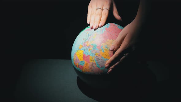 Girl's Hands Twist the Geographic Globe Around Its Axis