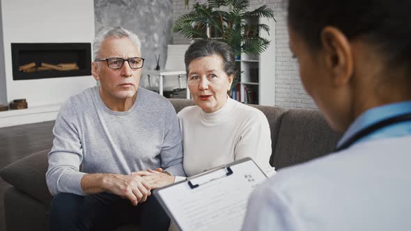 Doctor Female Announcing Good Test Results to Happy Elderly Patient and His Wife Who Sitting on Sofa