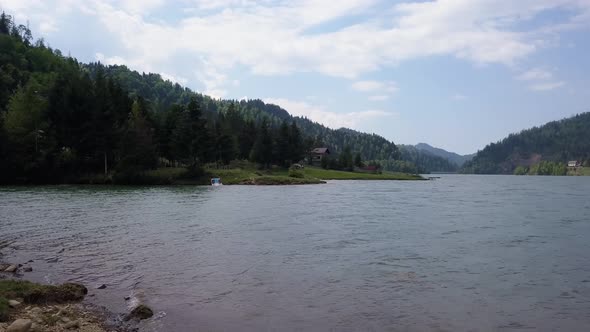 Aerial Panning Shot of edge of lake with trees in the background