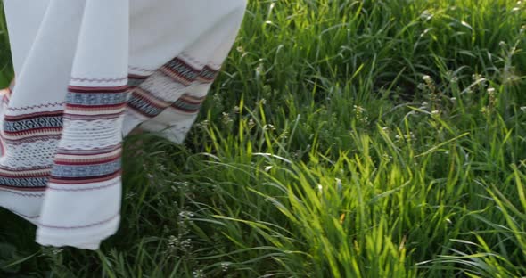 Girl in an Embroidered Dress Walks on the Grass Closeup of the Legs