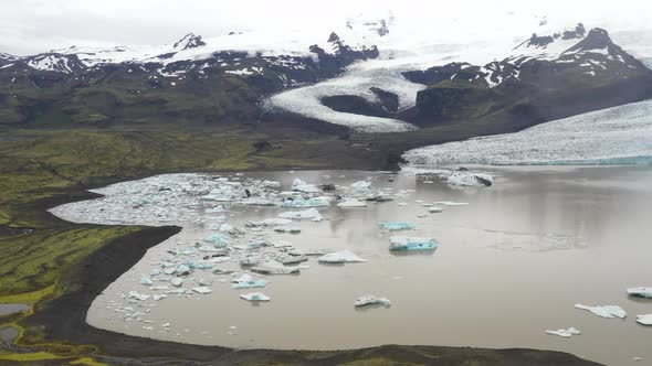 Iceland glacier with water, green grass and blue ice with drone video moving forward.