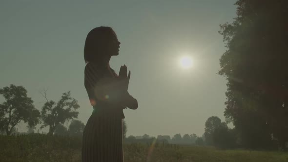Silhouette of Lovely Woman Praying Outdoors Over Beautiful Summer Sunrise