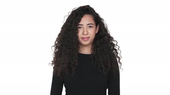 Portrait of Attractive Woman 20s Touching Her Dark Curly Hair Smiling Being in Good Mood Over White