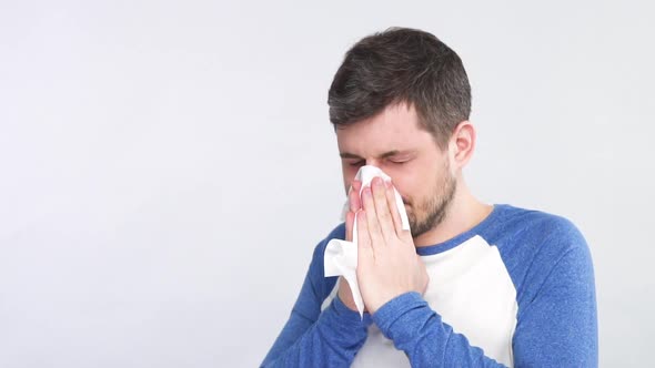 Sick Man with Symptoms of Flu Sneezing Nose in White Tissue Isolated on Grey Background