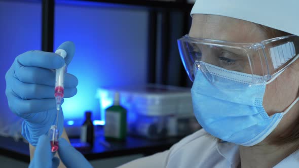 Woman doctor in protective gear and wear is holding syringe with vaccine for preventive medications