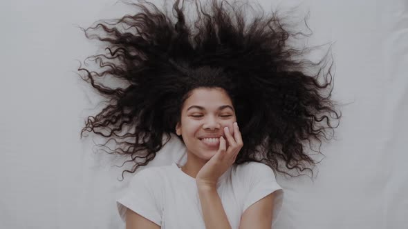 Beautiful Young Woman Lying on Bed and Laughing