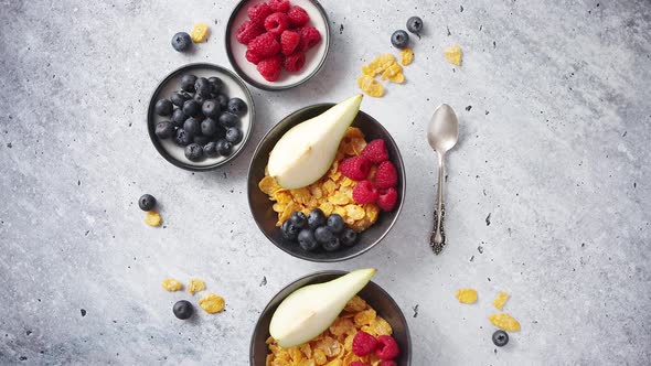 Golden Cornflakes with Fresh Fruits of Raspberries, Blueberries and Pear in Ceramic Bowl