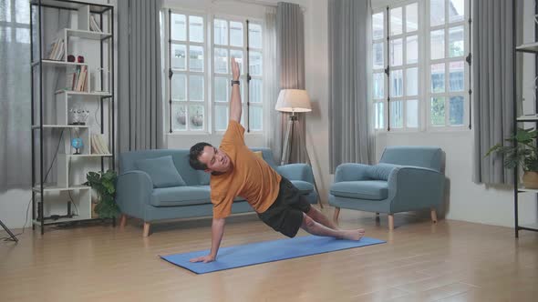 Asian Man Doing Yoga In Side Plank Pose On Mat At Home