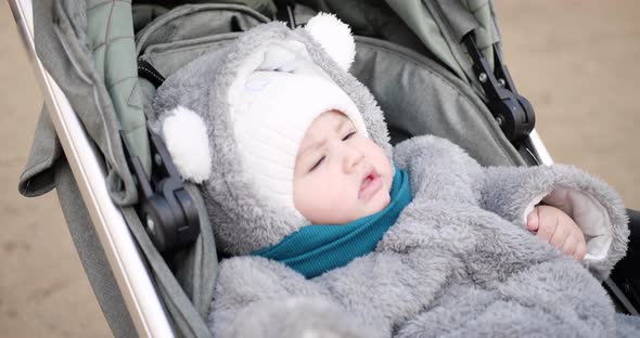 Baby Boy Rides in a Stroller in Winter in Sunny Weather