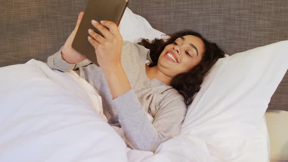 Woman lying on bed using her tablet in the bedroom 4K 4k