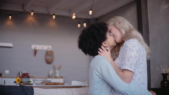 Lesbian Young Couple Kiss Hugging and Smiling Sitting on a Couch