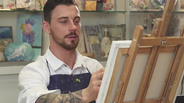 Handsome Bearded Male Artist Working on a Painting at His Art Studio