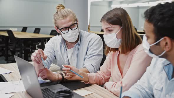 Multiethnic Diverse Employees in Protective Masks Working at Laptop Discussing Startup Project