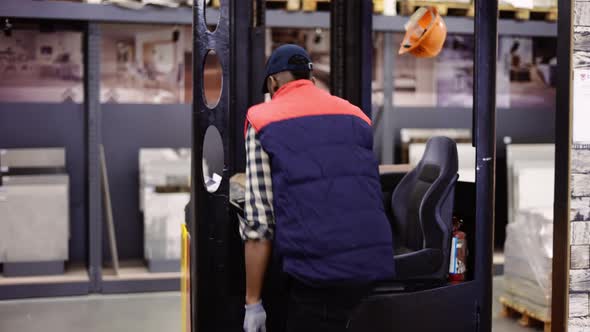 Forklift Operator in the Warehouse Wearing Uniform and Cap