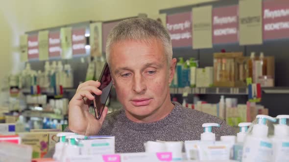 Senior Man Talking on the Phone While Shopping at the Pharmacy