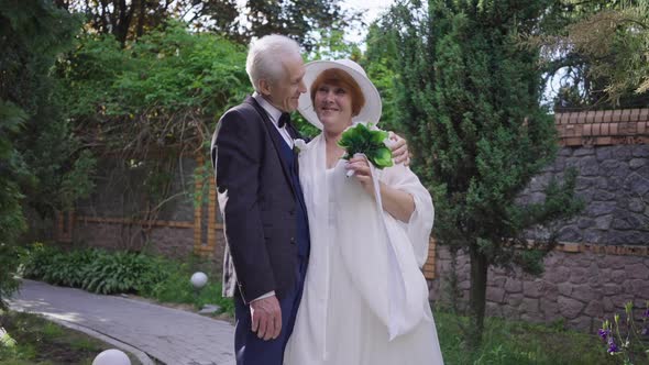 Portrait of Loving Caucasian Senior Bride and Groom Hugging Looking at Camera Smiling Standing