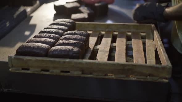 Baker's Hands Putting Freshly Baked Loaves of Rye Bread on a Tray in the Factory