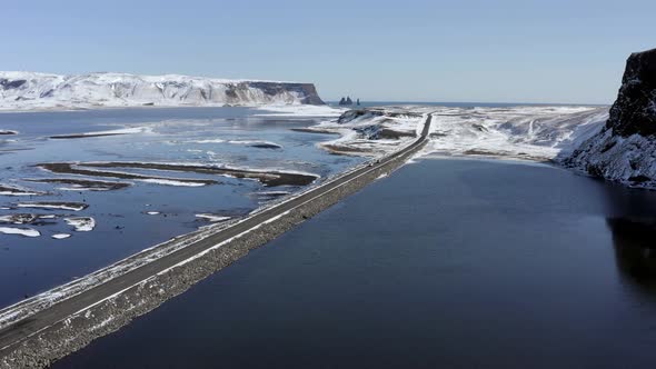 Cars Driving Along a Narrow Road Crossing a Lake in Iceland