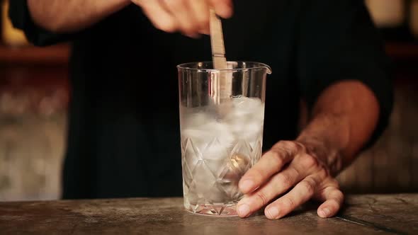 Bartender stirring ice cubes in glass