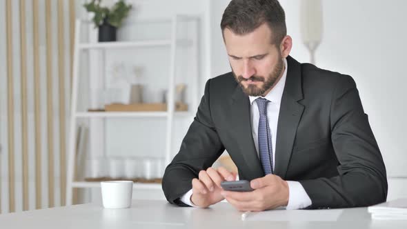 Astonished Businessman Shocked By Result on Smartphone Wondering