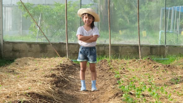 Little girl wearing a hat helps her mother in the garden.