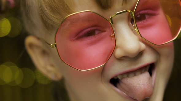 Close Up Face of Child. Smiling, Looking at Camera. Girl in Pink Sunglasses Posing