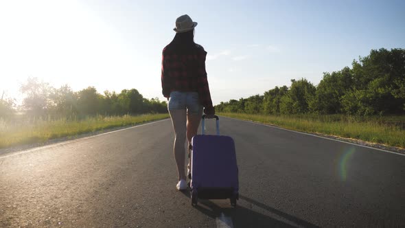 Young Woman with a Suitcase on Road. Funny Beautiful Girl Traveler. Travel Concept Video.