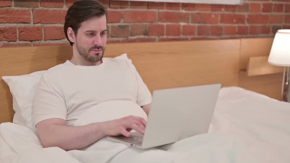 Young Businessman Working on Laptop in Bed