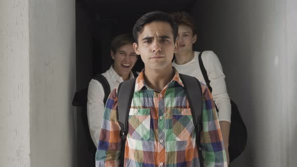 Portrait of Sad Bullied Caucasian Boy Looking at Camera As Classmates Laughing at the Background