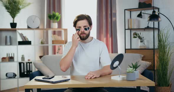 Guy Poses at Camera with Anti-Aging Hydrogel Eye-Patches Sitting at the Table