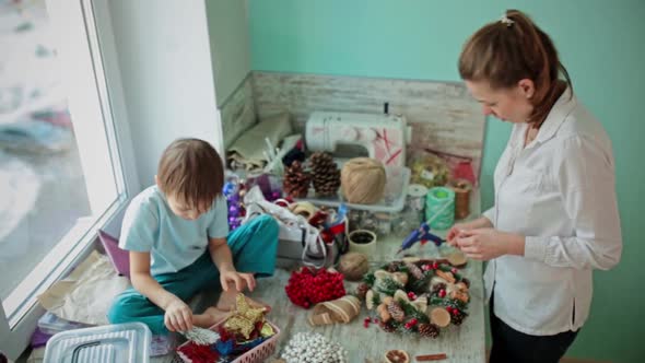 A Girl and a Child Collect a Christmas Wreath Together